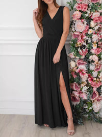 Woman wearing a black dress with a slit standing next to a floral arrangement.