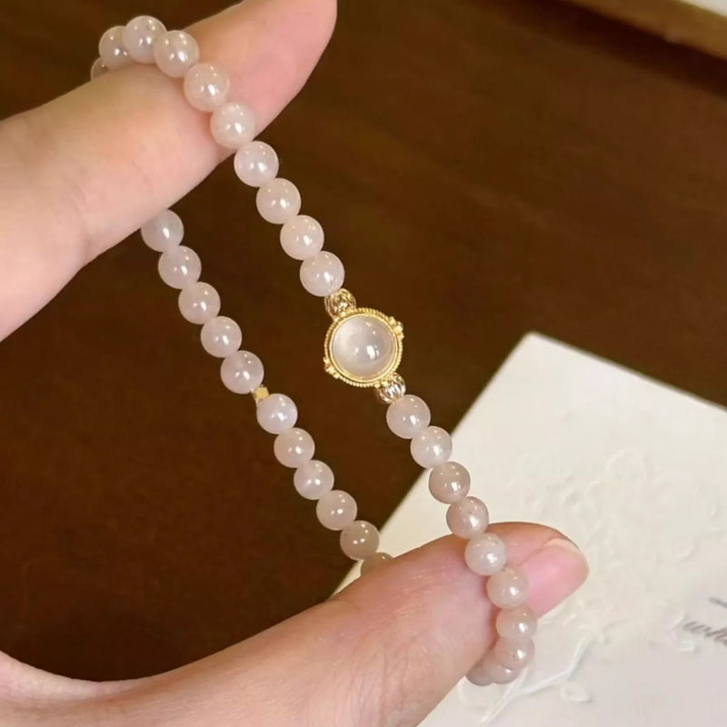 Hand holding a beaded bracelet with a gold clasp against a blurred background