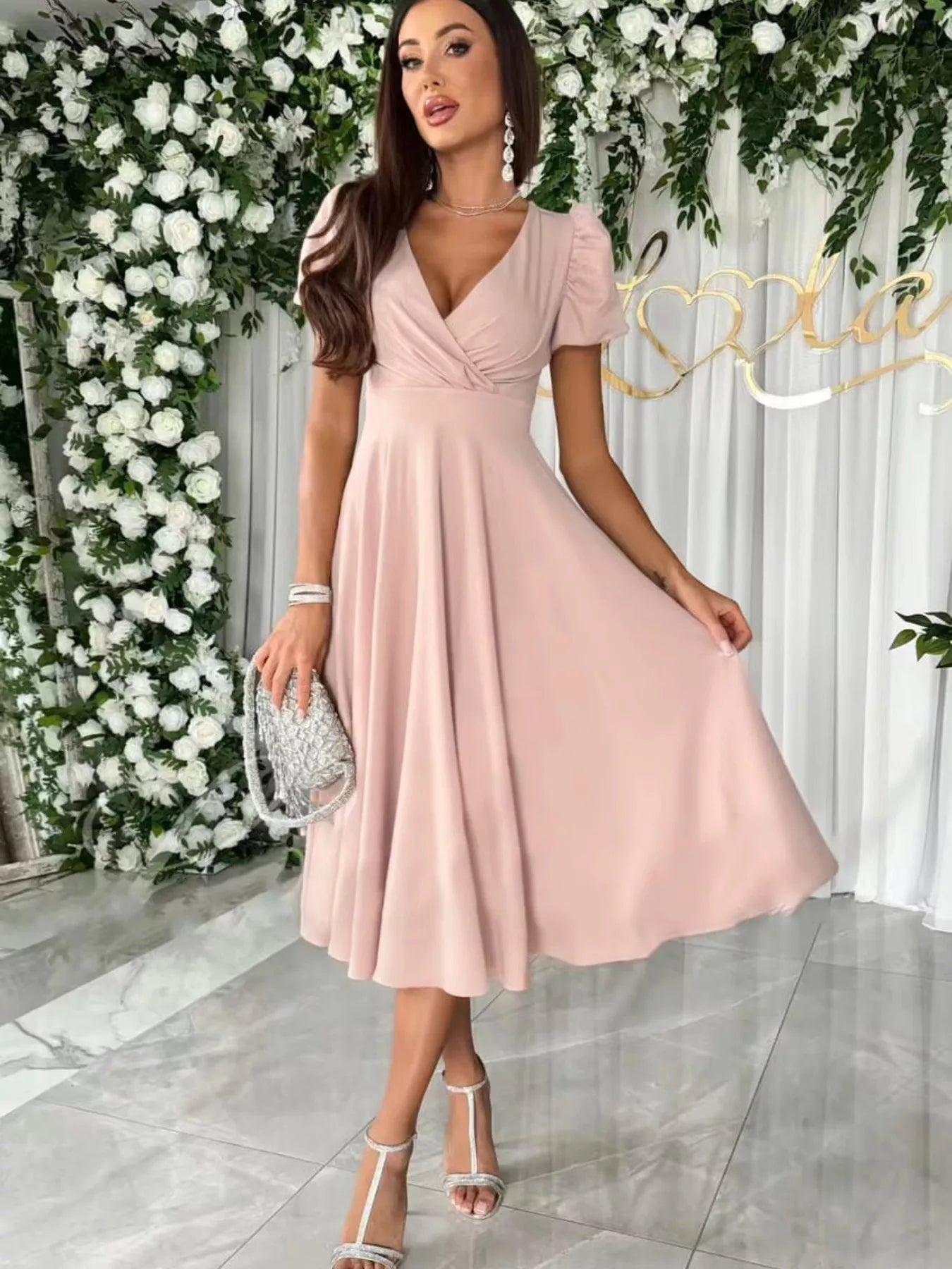 Woman in a pink dress standing in front of floral decorations