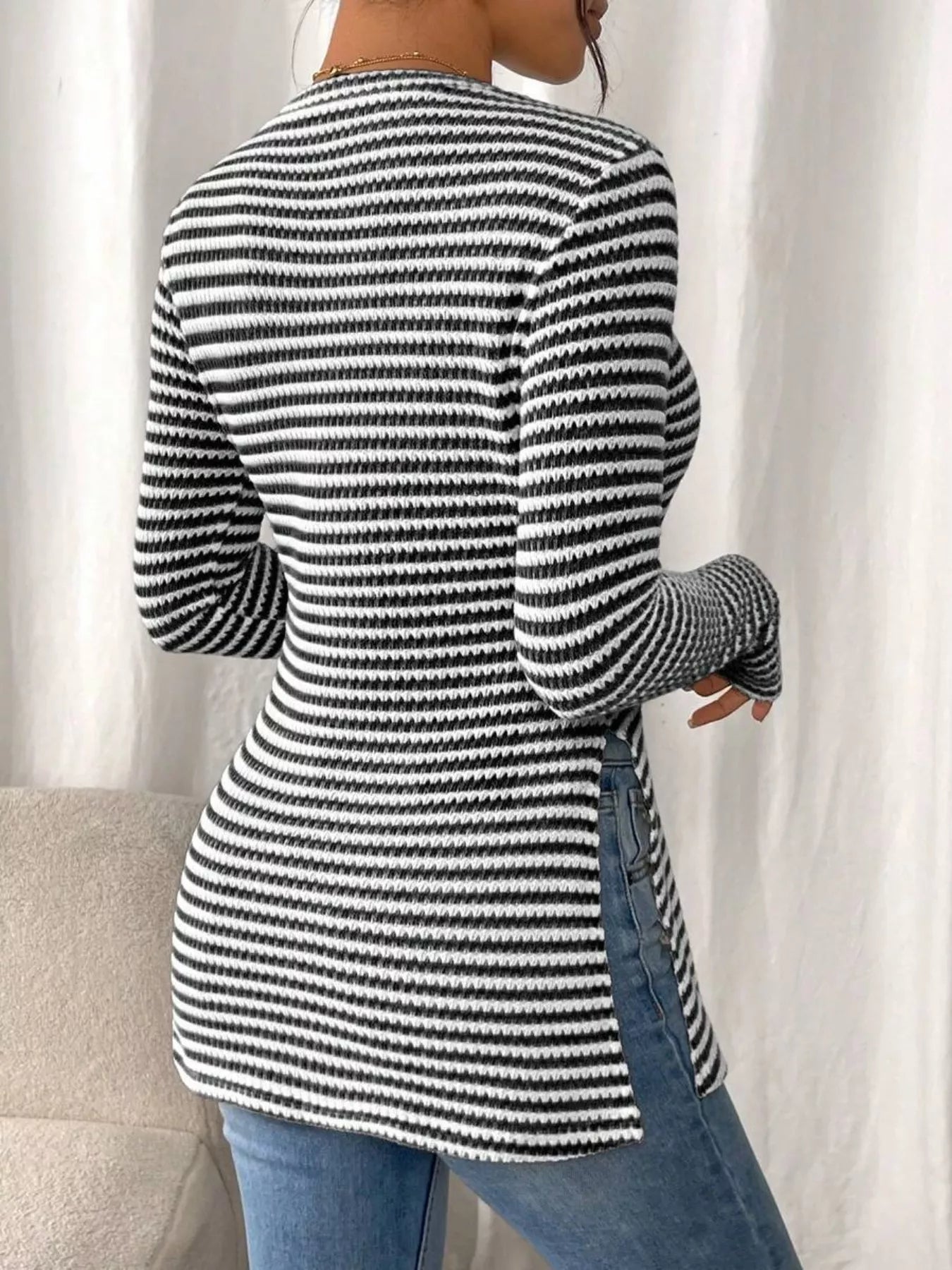 Person wearing a black and white striped sweater with a neutral background