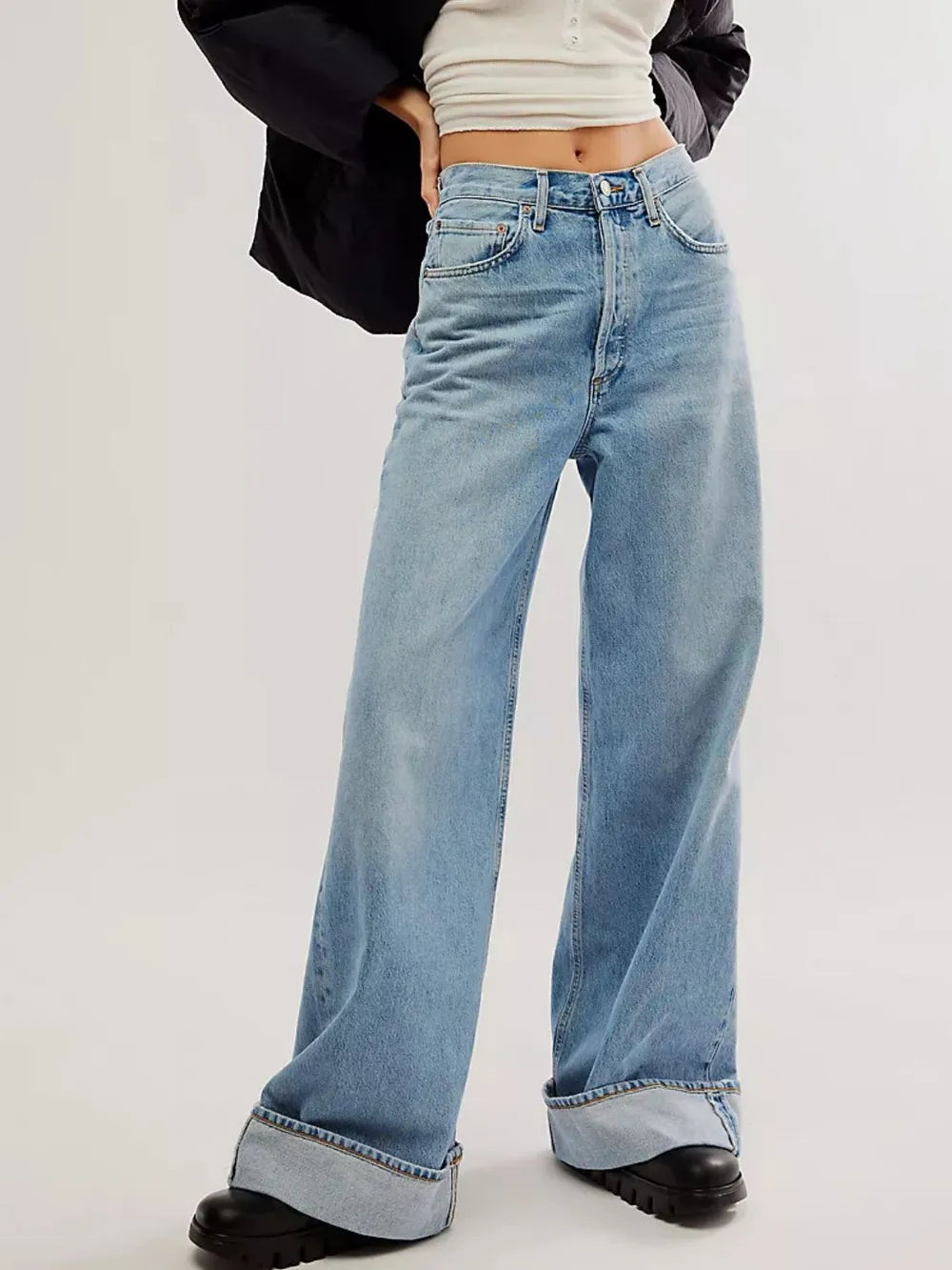 Person wearing light blue wide-leg jeans on a plain background