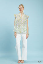 Woman wearing a floral blouse and white pants on a light blue background