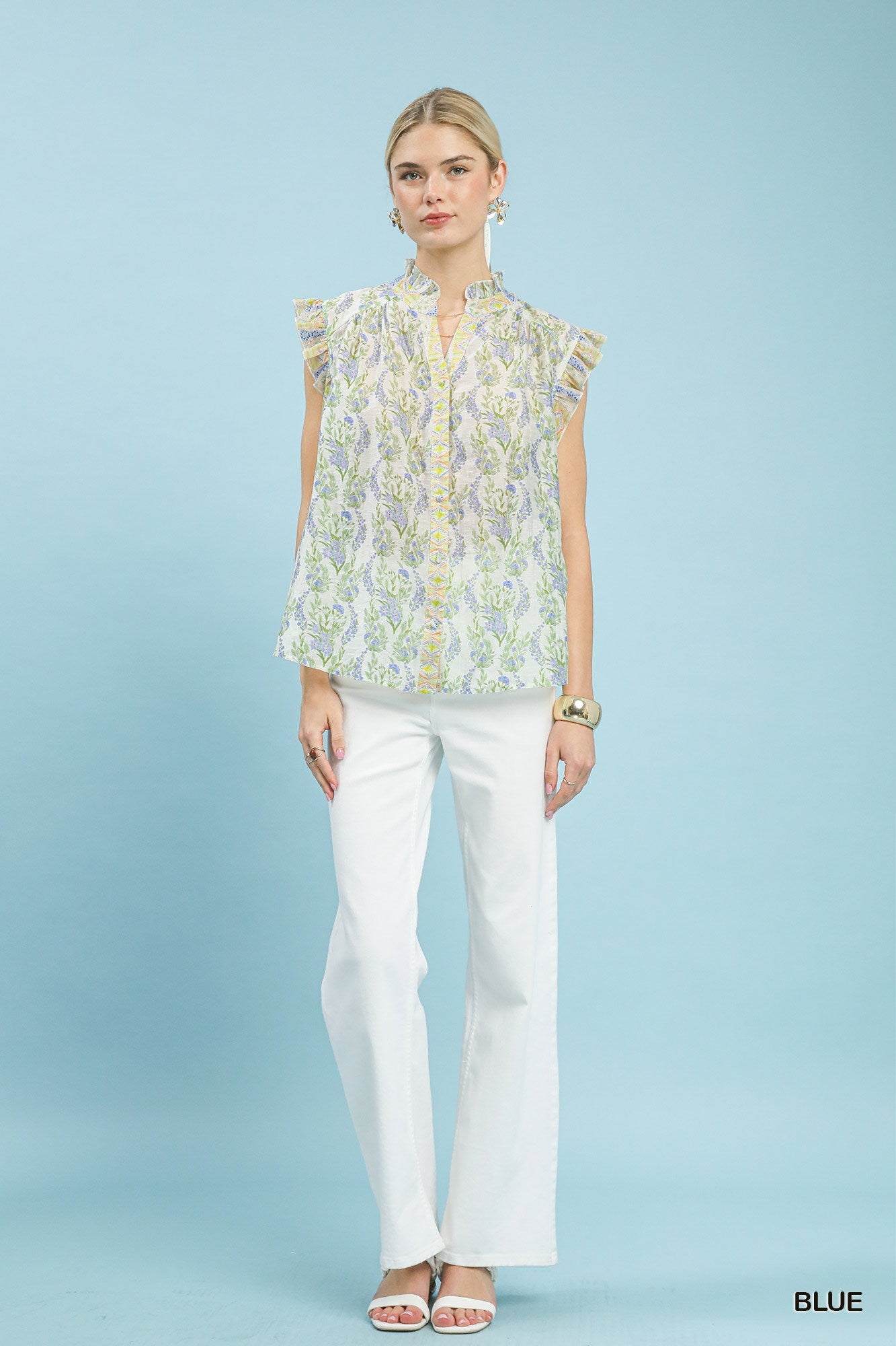 Woman wearing a floral blouse and white pants on a light blue background