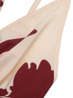 Beige bikini top with red abstract design on a white background