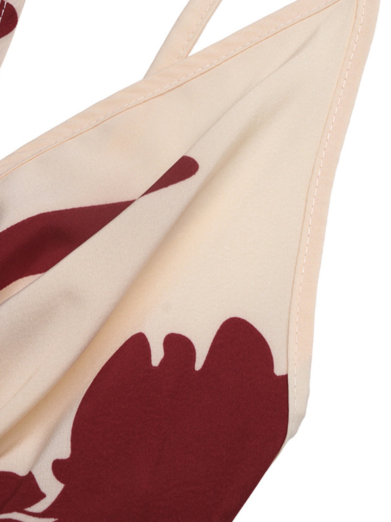 Beige bikini top with red abstract design on a white background