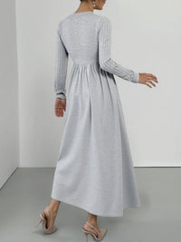 Woman wearing a long gray dress against a plain background