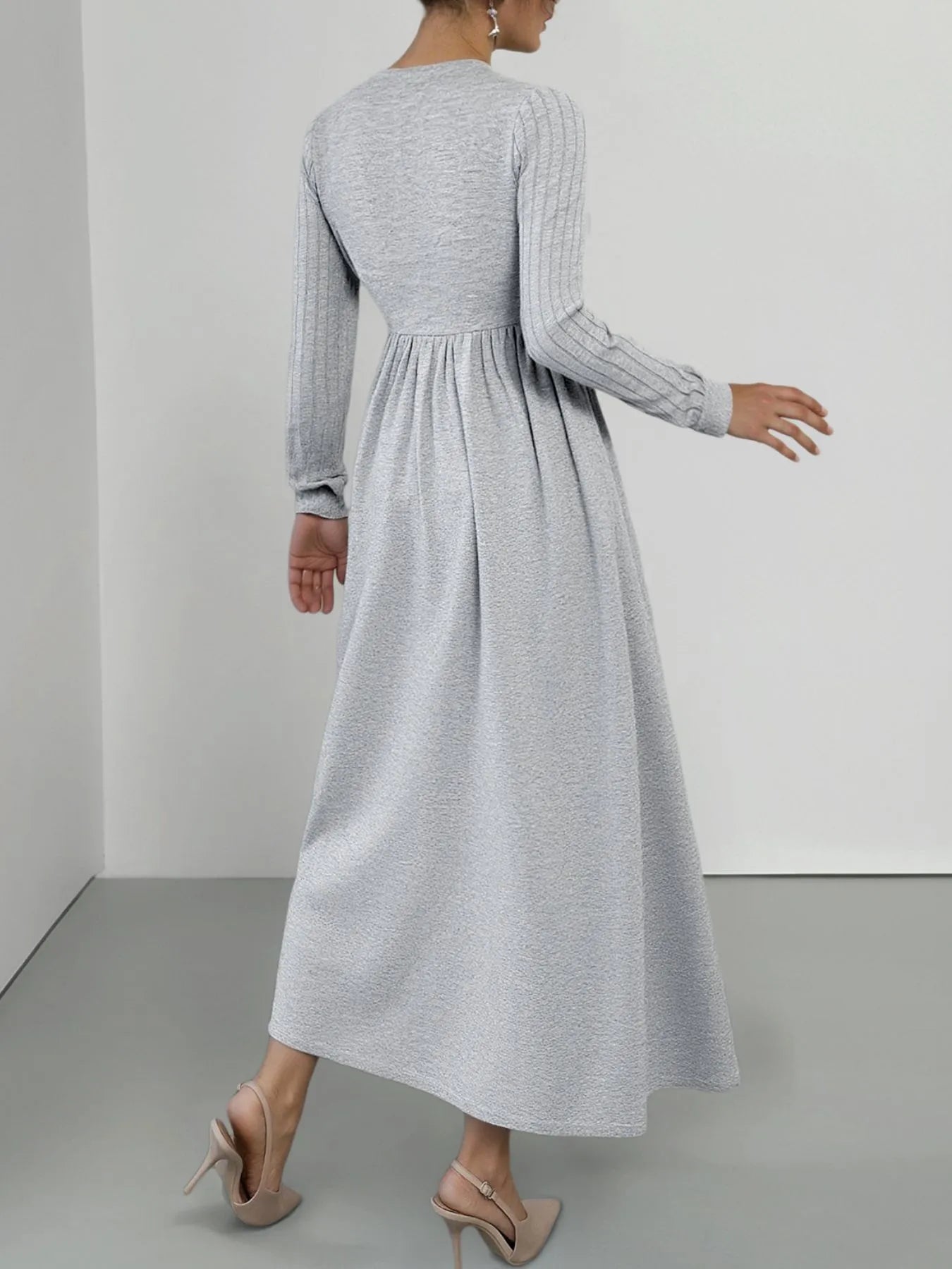 Woman wearing a long gray dress against a plain background