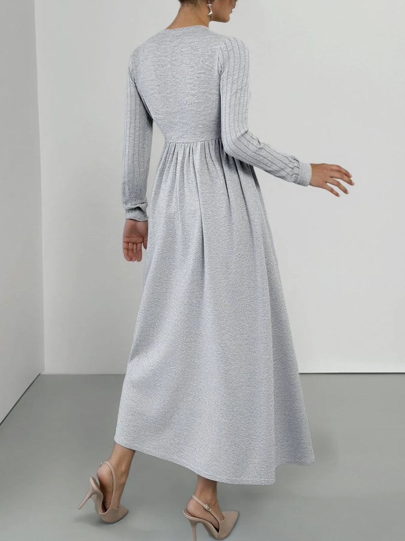 Woman wearing a long gray dress against a plain background