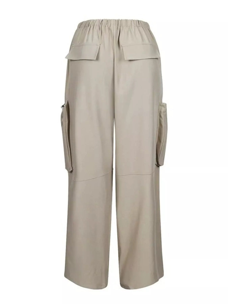 A pair of wide-leg cargo pants in a light beige or khaki color, featuring an elastic waistband, flap cargo pockets on the sides, and utility pockets on the upper thighs, shown against a plain white background.