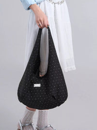 Person holding a black polka dot bag against a plain background