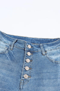 Close-up of blue denim jeans with button details on a white background