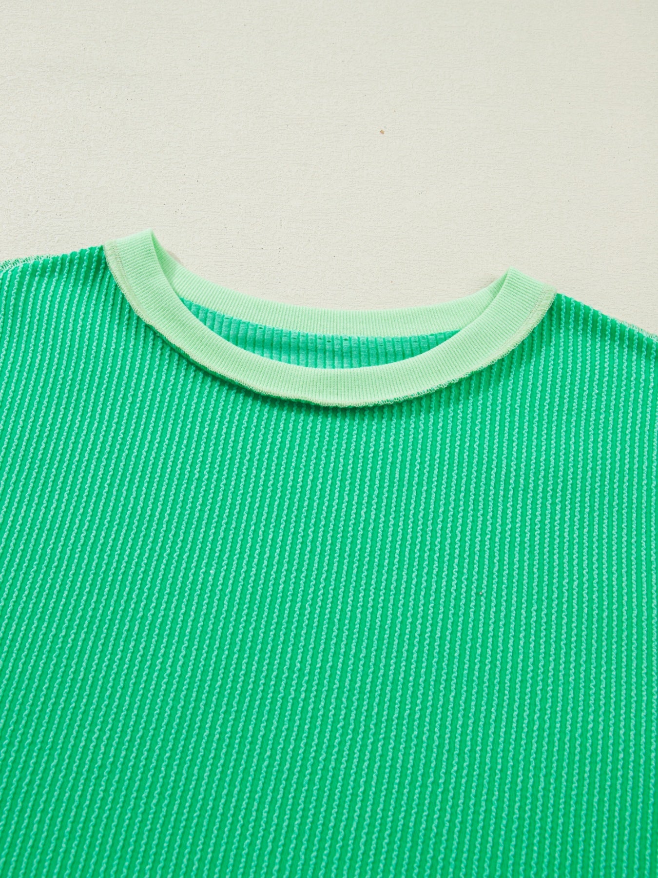 Green shirt with a light green collar on a beige background