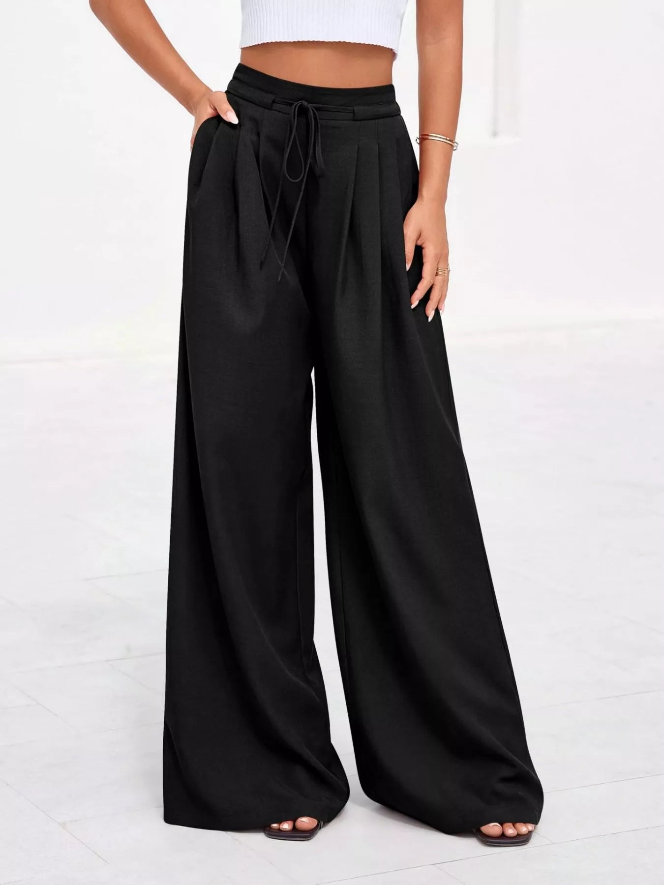 Black wide-leg pants worn by a person on a white background