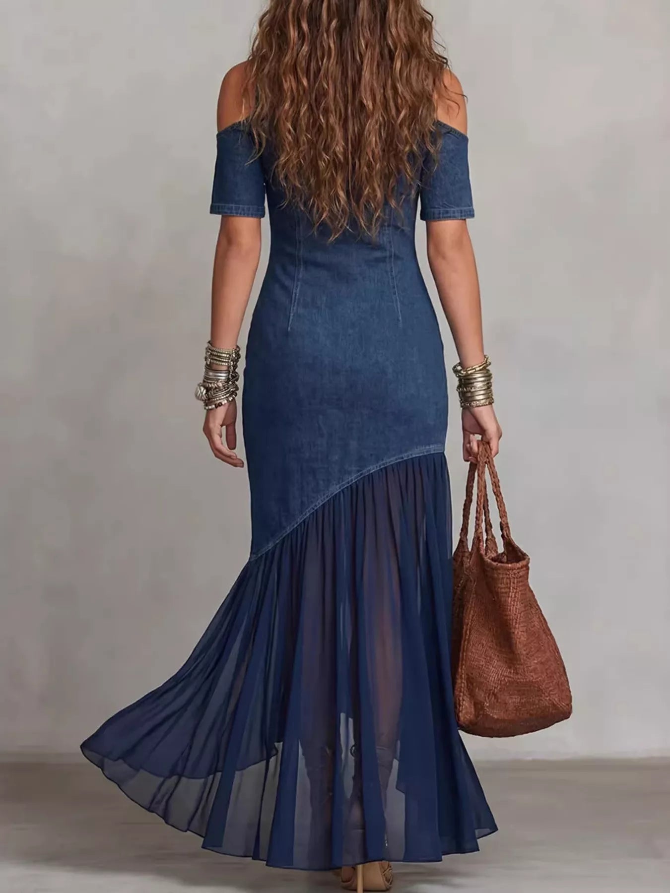 Woman wearing a blue dress with a brown bag against a neutral background