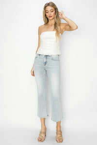 Woman wearing a white strapless top and light blue jeans on a white background