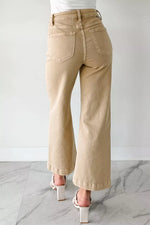Beige wide-leg pants worn by a person on a marble floor with a white background