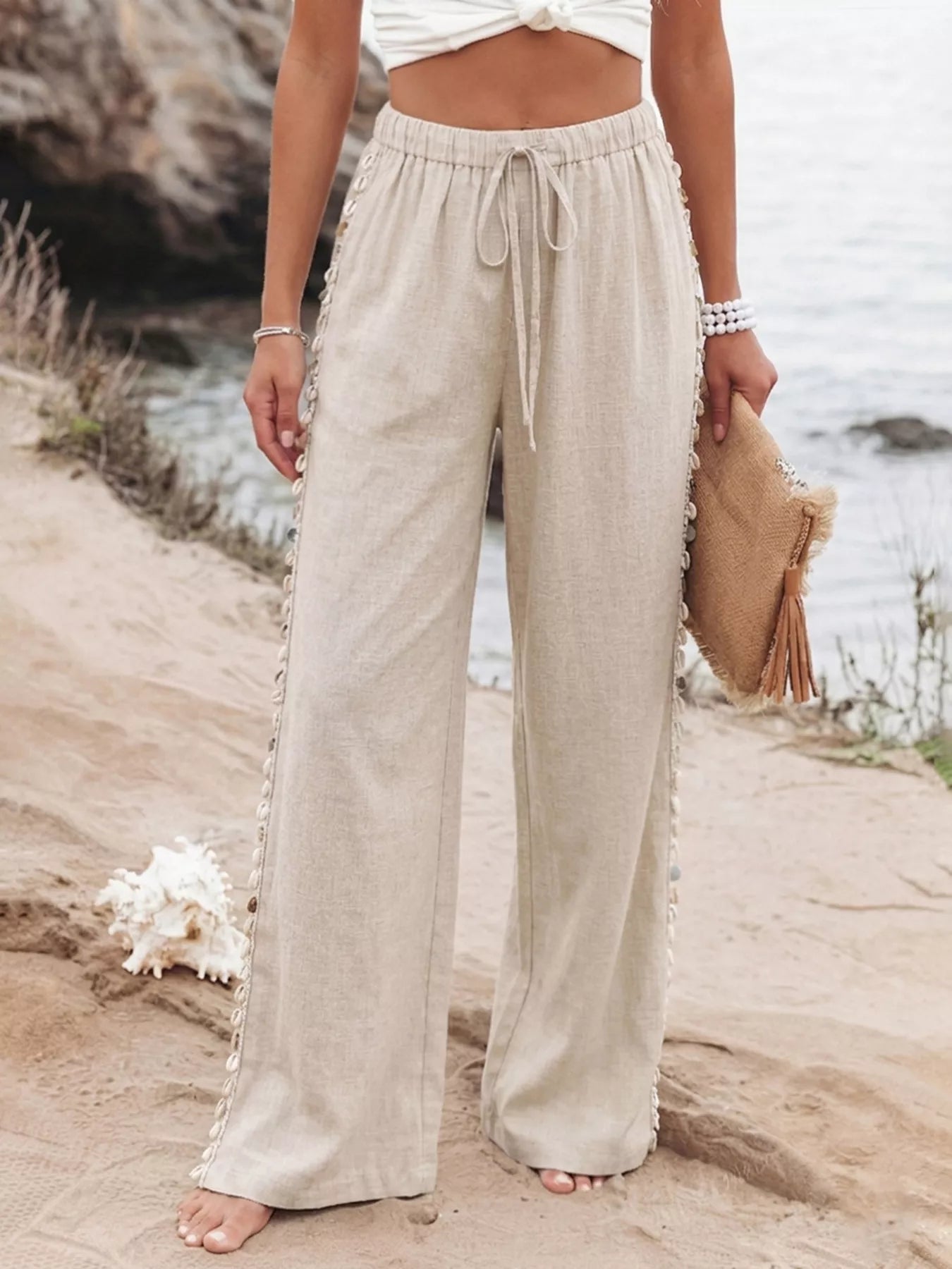 Person wearing beige wide-leg pants by a body of water.