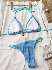 Blue bikini set on a beige surface with accessories.