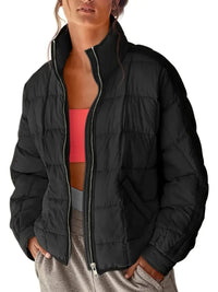Person wearing a black puffer jacket over a pink sports bra and gray leggings on a white background