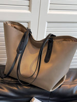 Beige handbag with black straps on a leather surface with a white background