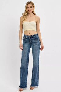 Woman wearing a beige crop top and blue jeans on a white background