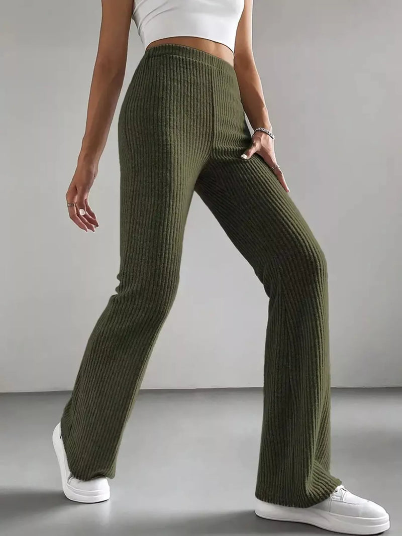 Person wearing green ribbed pants and white sneakers on a gray background