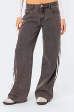 Person wearing wide-leg jeans with side stripes on a white background