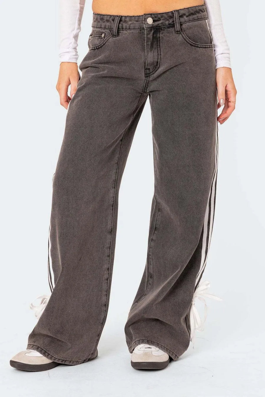 Person wearing wide-leg jeans with side stripes on a white background