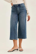Person wearing blue jeans on a plain background