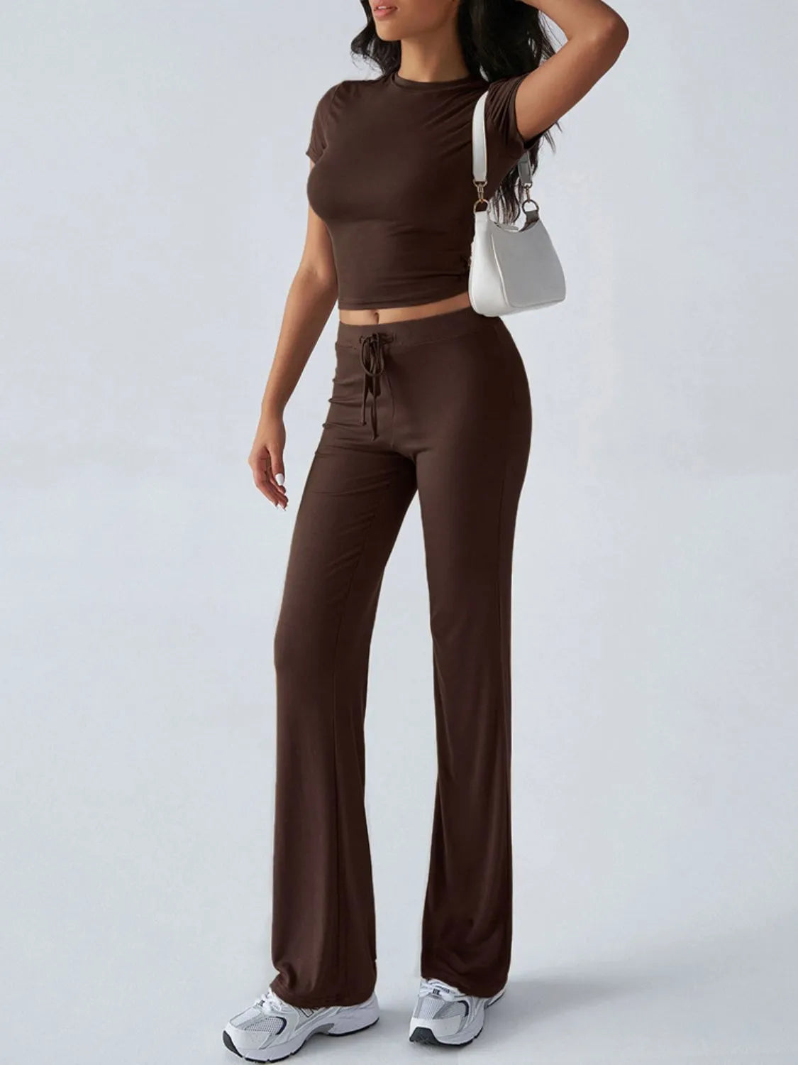 Woman wearing a brown outfit with wide-leg pants and a crop top on a white background