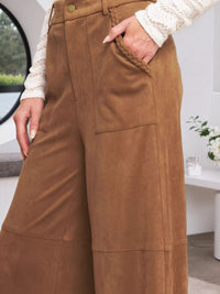 Brown pants worn by a person with a blurred indoor background