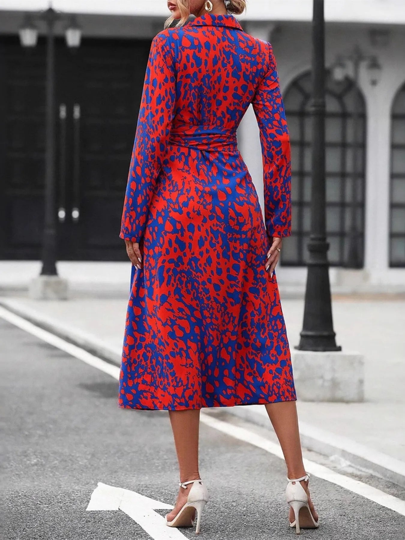 Woman wearing a red and blue patterned dress on a city street.
