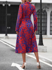 Woman wearing a red and blue patterned dress on a city street.