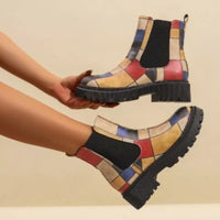 Colorful patterned boots with a checkered design held by a person against a beige background