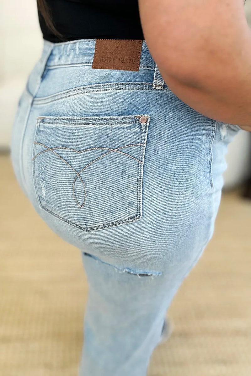 Light blue jeans with a brand label on the back pocket against a neutral background