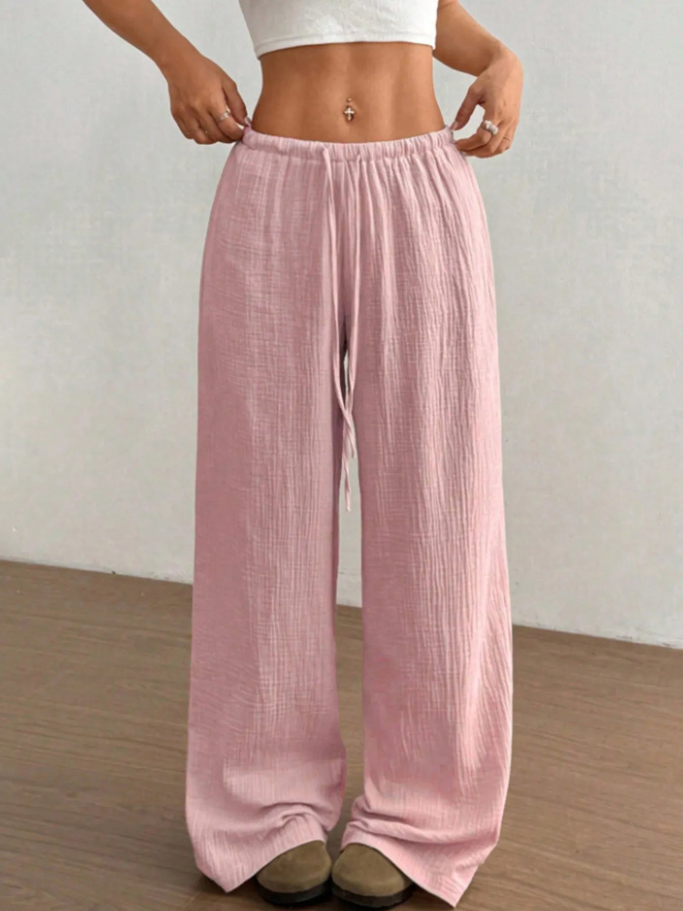 Person wearing light pink wide-leg pants against a plain background