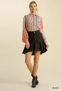 Woman wearing a colorful striped shirt and black skirt on a beige background