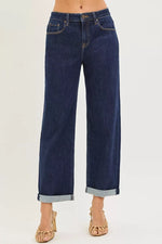 Dark blue jeans with rolled-up cuffs on a white background