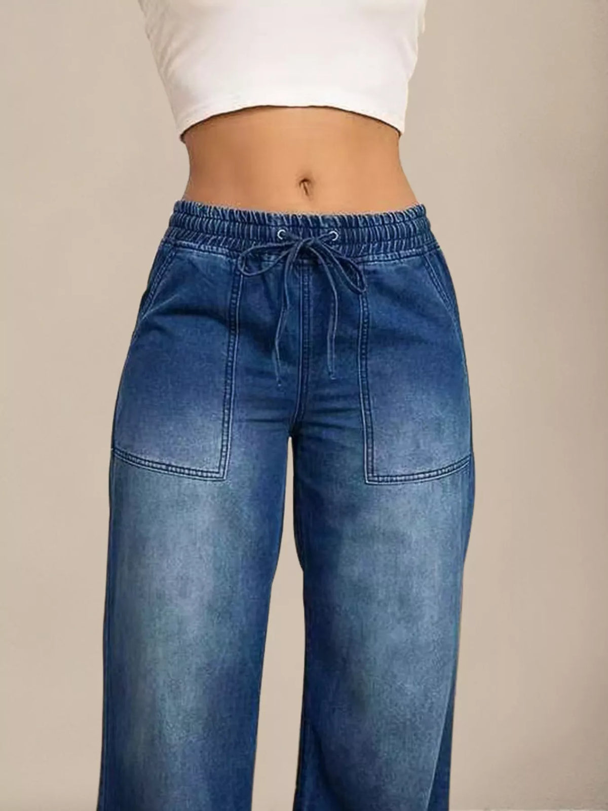 Blue jeans worn by a person on a beige background