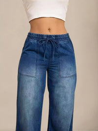 Blue jeans worn by a person on a beige background