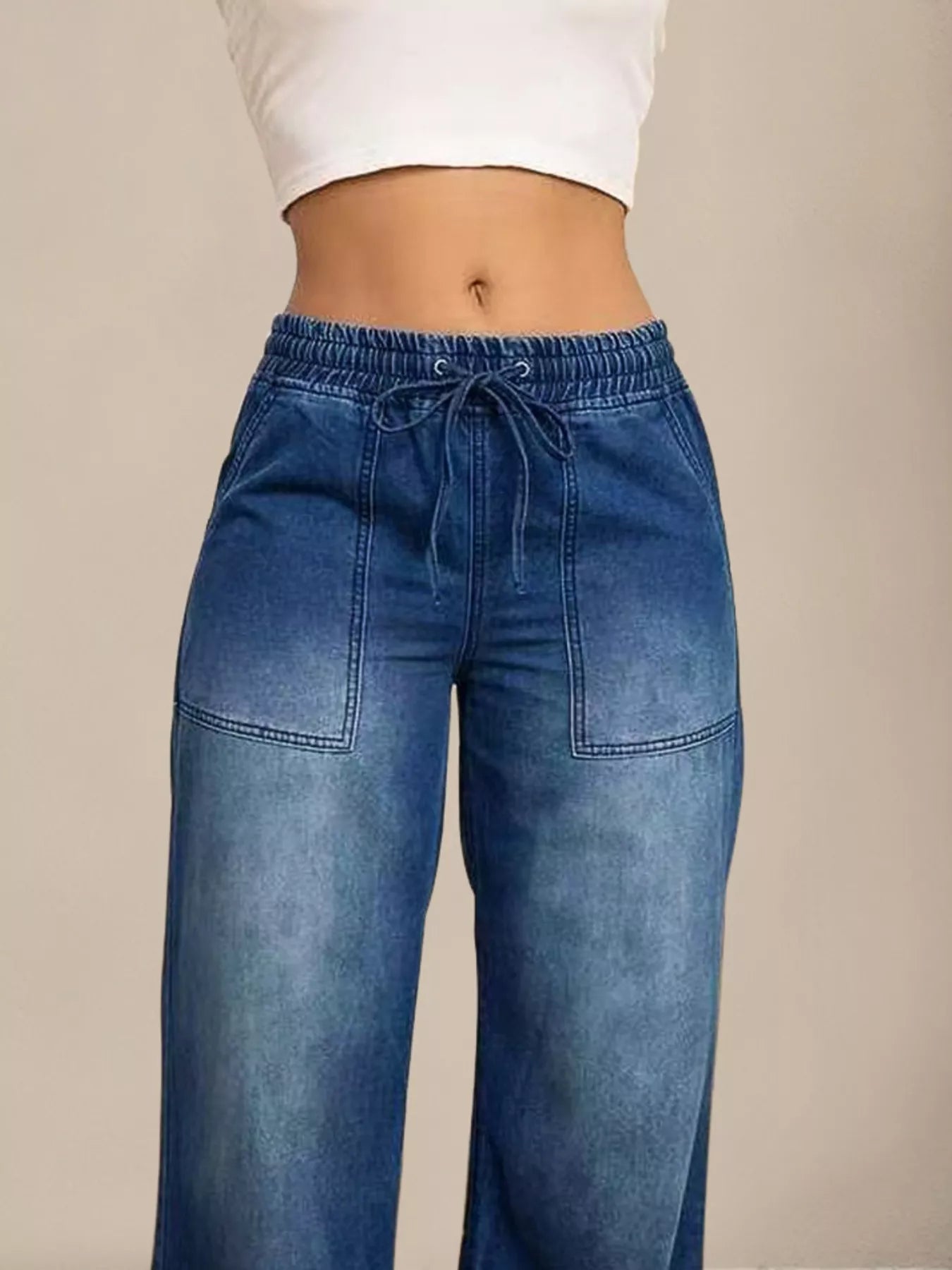 Blue jeans worn by a person on a beige background