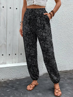 Person wearing black patterned pants against a gray wall.