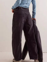 Person wearing dark wide-leg pants with a light blue top against a plain background