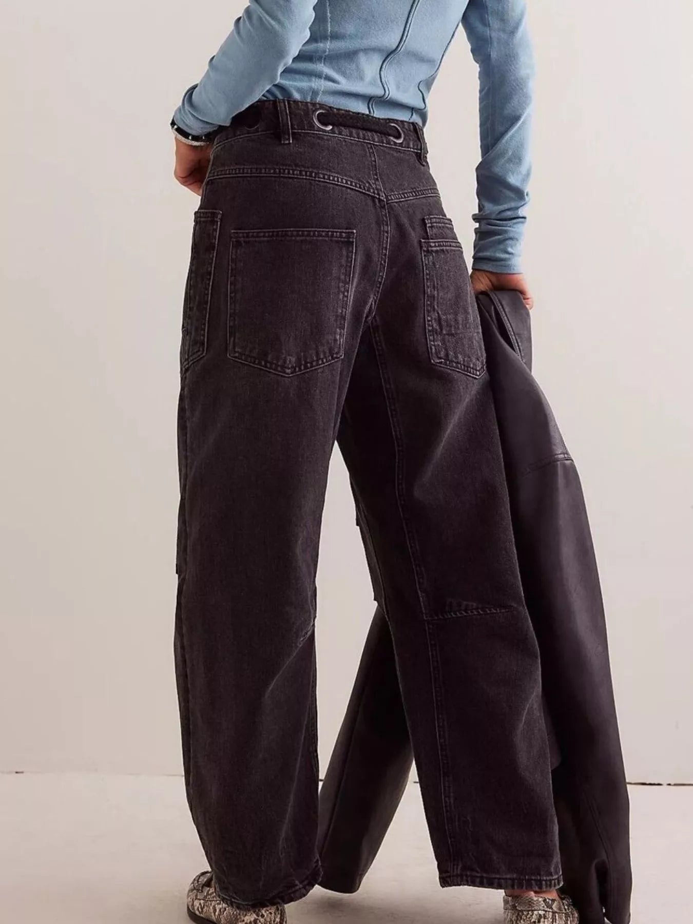 Person wearing dark wide-leg pants with a light blue top against a plain background