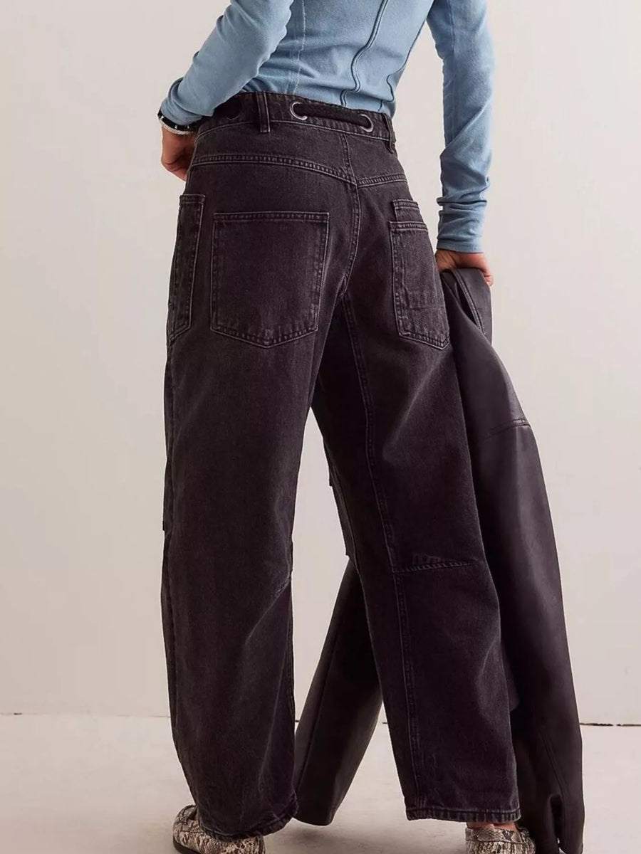 Person wearing dark wide-leg pants with a light blue top against a plain background