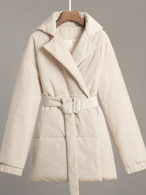 Beige puffer coat on a hanger against a gray background