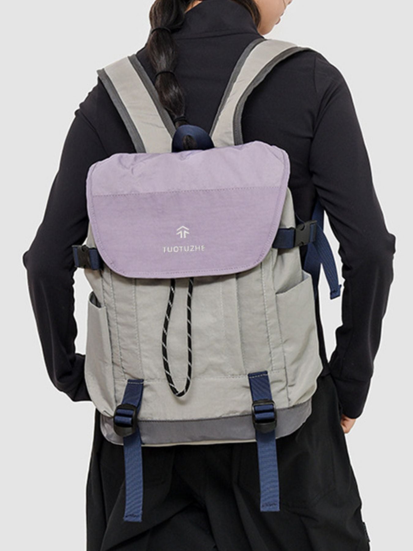 Person wearing a gray and purple backpack with a visible brand logo on a white background
