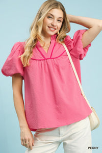 Woman wearing a pink blouse with puff sleeves against a light blue background