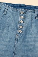 Close-up of blue denim jeans with button details on a beige background