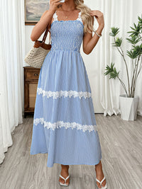 Woman wearing a blue and white striped dress with lace details in a room.